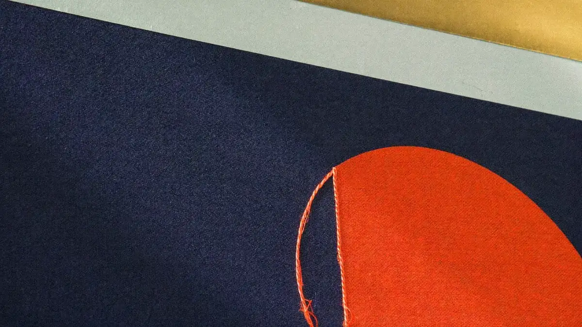 Close-up of navy cloth with a stitched vermilion inlay